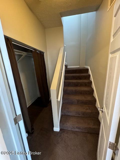 stairway with a textured ceiling, baseboards, and carpet floors