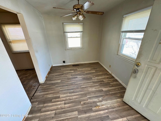 empty room with a ceiling fan, plenty of natural light, baseboards, and wood finished floors