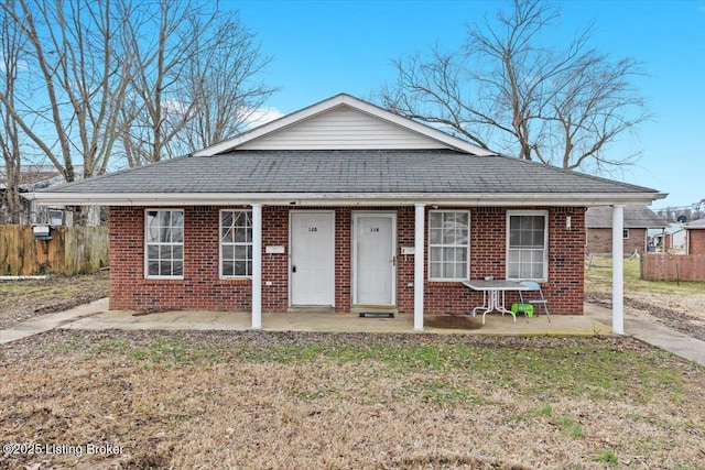 bungalow featuring a porch, brick siding, a shingled roof, and a front lawn