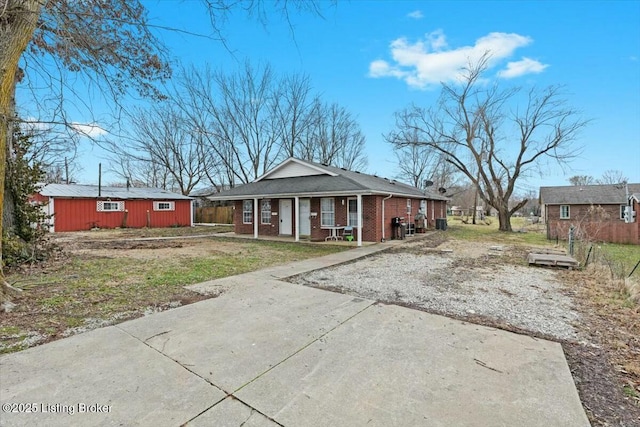 view of front of property with driveway, a porch, an outdoor structure, and brick siding