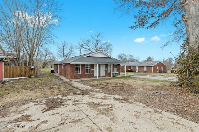 view of front of home with driveway, covered porch, fence, and brick siding