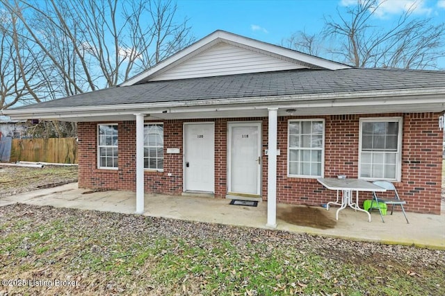 view of front of property with covered porch, roof with shingles, and brick siding