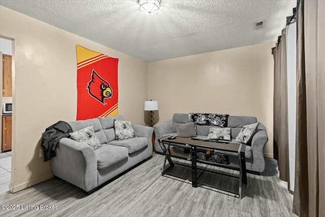 living room with visible vents, a textured ceiling, and light wood-style flooring