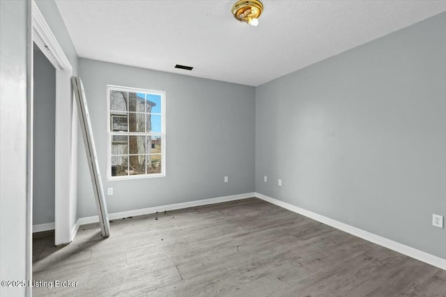 unfurnished bedroom with visible vents, baseboards, and wood finished floors