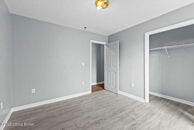 unfurnished bedroom featuring a closet, baseboards, and wood finished floors