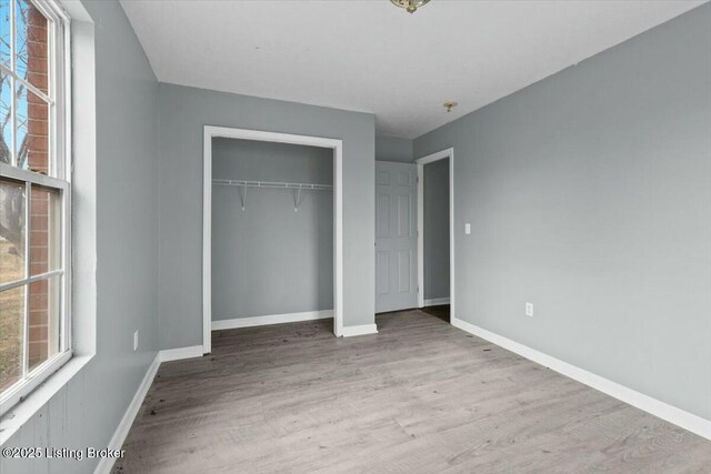 unfurnished bedroom with a closet, baseboards, and wood finished floors