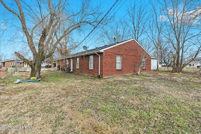 view of home's exterior featuring brick siding, a lawn, and central AC