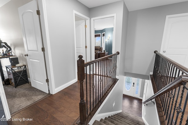 hall featuring baseboards, an upstairs landing, and wood finished floors