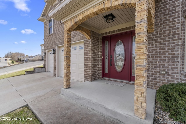 property entrance featuring a garage, brick siding, and driveway