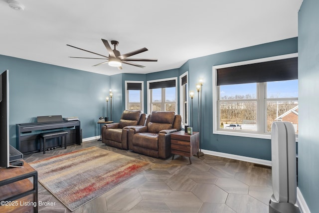 living area with baseboards and ceiling fan