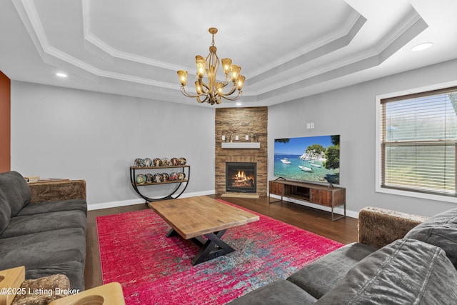 living area with crown molding, baseboards, a stone fireplace, wood finished floors, and a raised ceiling