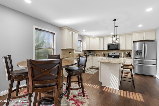 kitchen with stainless steel appliances, backsplash, a breakfast bar area, and dark wood-style flooring