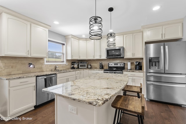 kitchen with a kitchen breakfast bar, a center island, stainless steel appliances, decorative backsplash, and dark wood-style flooring