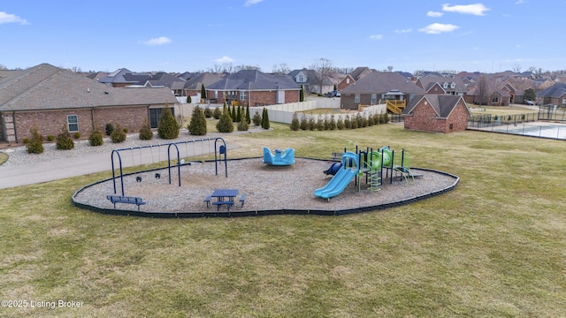 communal playground featuring a yard, a residential view, and fence