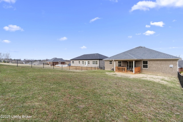 back of house featuring a lawn, roof with shingles, a fenced backyard, and brick siding