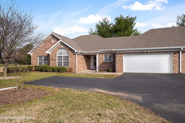 single story home with aphalt driveway, brick siding, a garage, and a front yard