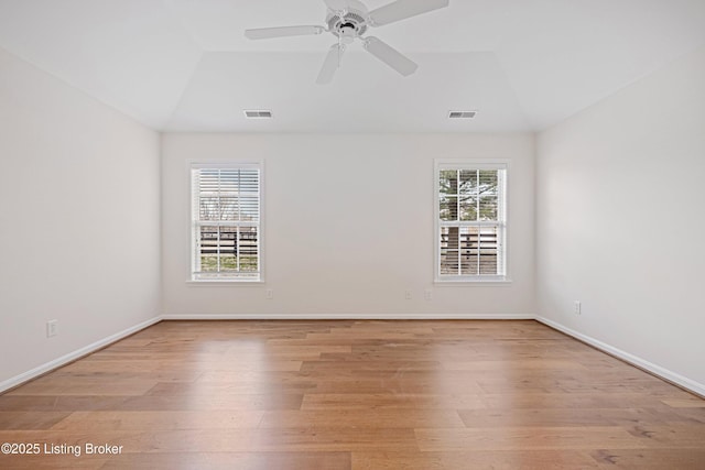 spare room featuring visible vents, lofted ceiling, and light wood-style flooring