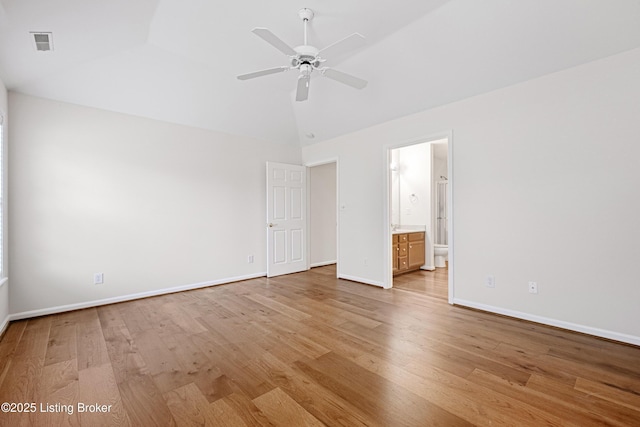 unfurnished bedroom featuring visible vents, baseboards, light wood-type flooring, vaulted ceiling, and ensuite bathroom