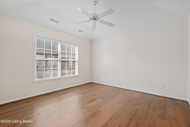 spare room featuring ceiling fan, wood finished floors, visible vents, and baseboards