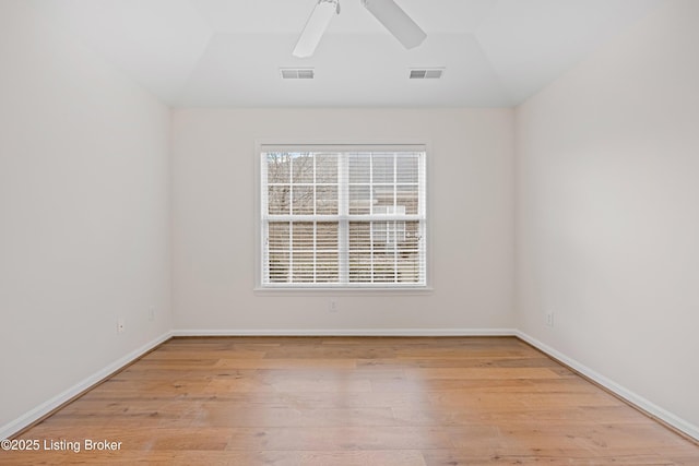 empty room with baseboards, ceiling fan, vaulted ceiling, and light wood finished floors