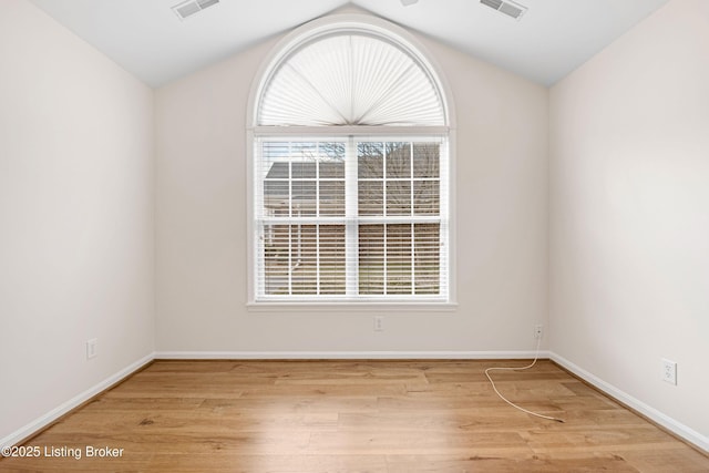 unfurnished room featuring visible vents, lofted ceiling, baseboards, and wood finished floors