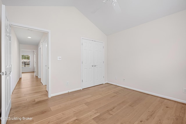 unfurnished bedroom featuring ceiling fan, baseboards, light wood-type flooring, a closet, and high vaulted ceiling