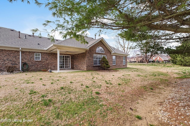 back of house featuring a patio, fence, roof with shingles, a yard, and brick siding