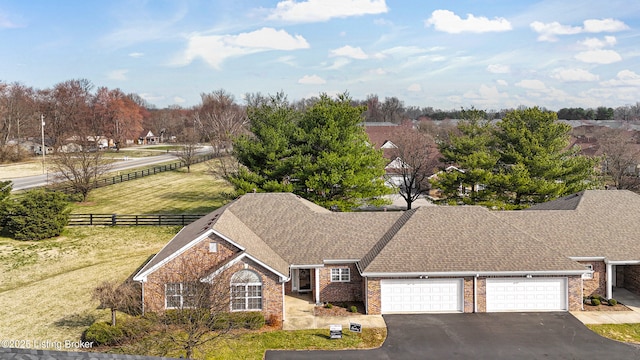 view of front of property with a garage, brick siding, driveway, and fence