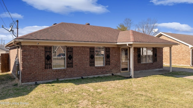 view of front of house featuring fence, brick siding, a front lawn, and a shingled roof