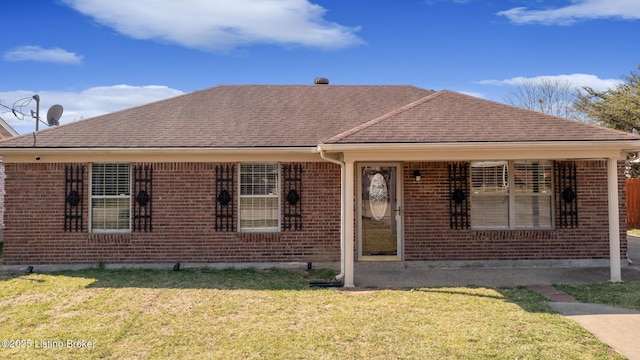 view of front of home featuring brick siding, a front yard, and roof with shingles