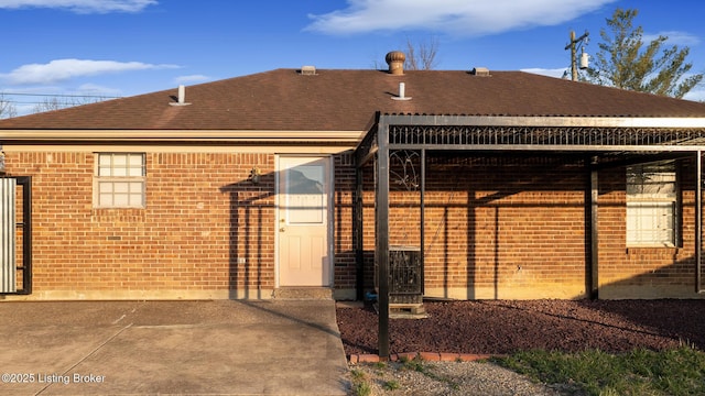 exterior space featuring brick siding and a shingled roof