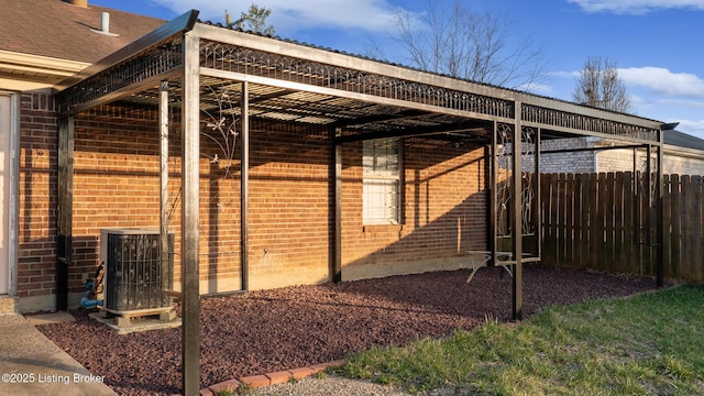 view of property exterior with brick siding, cooling unit, and fence