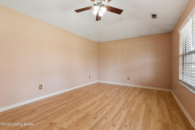 spare room featuring a ceiling fan, lofted ceiling, baseboards, and light wood-type flooring