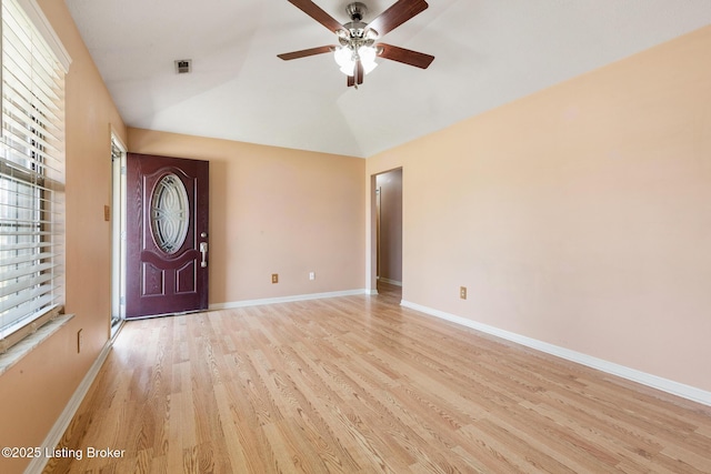 entrance foyer with visible vents, baseboards, light wood-style flooring, ceiling fan, and vaulted ceiling