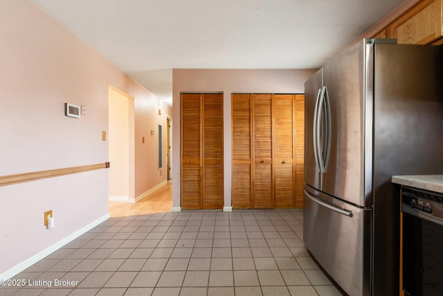 kitchen with dishwasher, light tile patterned floors, baseboards, and freestanding refrigerator