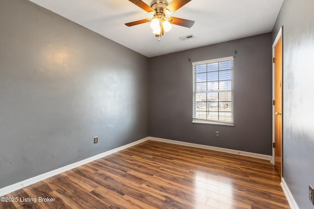 spare room featuring visible vents, a ceiling fan, baseboards, and wood finished floors