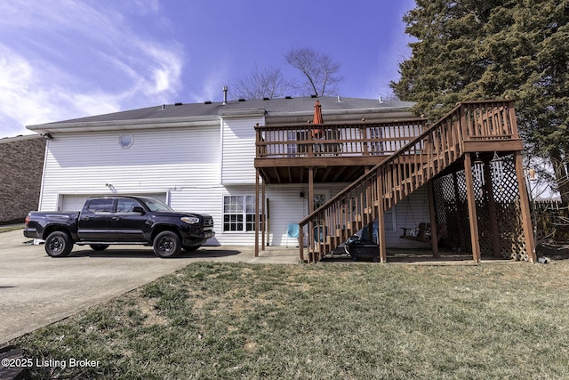 back of house featuring stairway, a lawn, a deck, and driveway