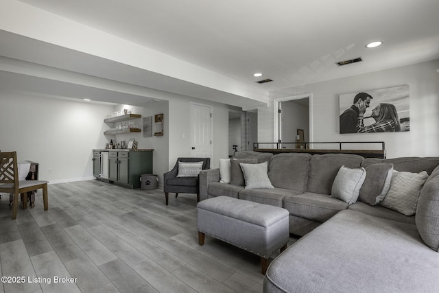 living area with recessed lighting, visible vents, a bar, and light wood finished floors