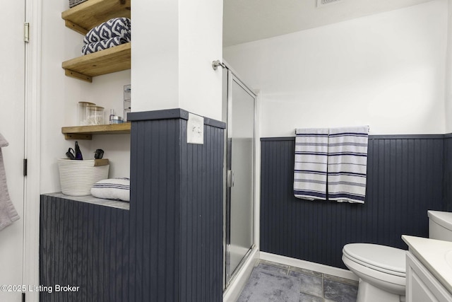 bathroom featuring vanity, toilet, a shower stall, and wainscoting