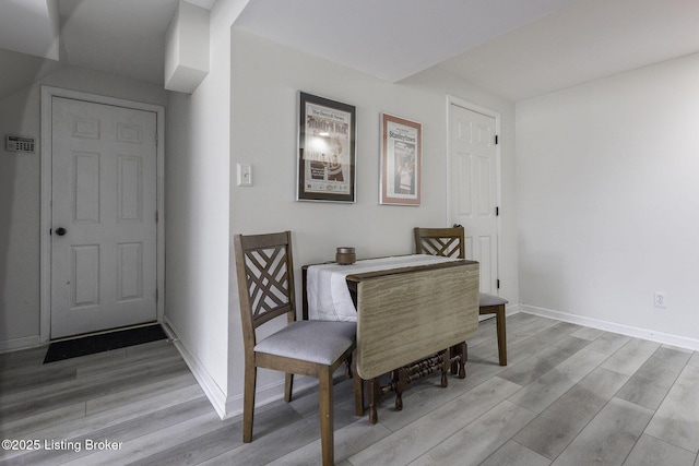 dining space featuring light wood-style floors and baseboards