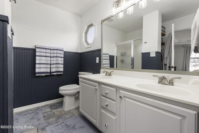 full bathroom with a stall shower, wainscoting, and a sink