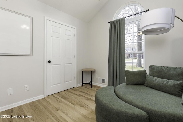 sitting room featuring visible vents, baseboards, light wood-type flooring, and lofted ceiling