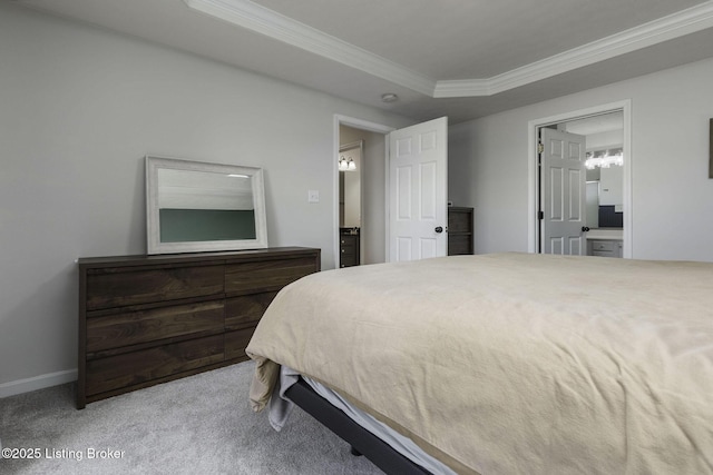 bedroom with carpet, baseboards, a tray ceiling, ornamental molding, and ensuite bathroom