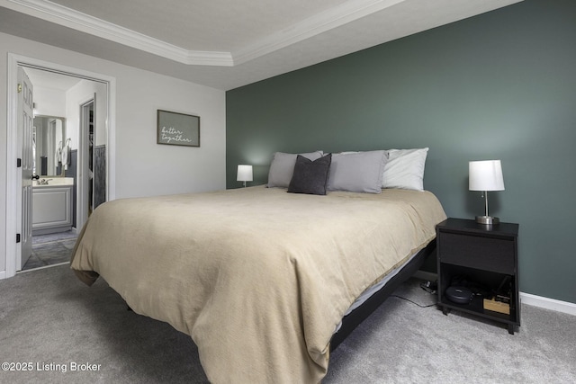 carpeted bedroom with connected bathroom, crown molding, and a raised ceiling