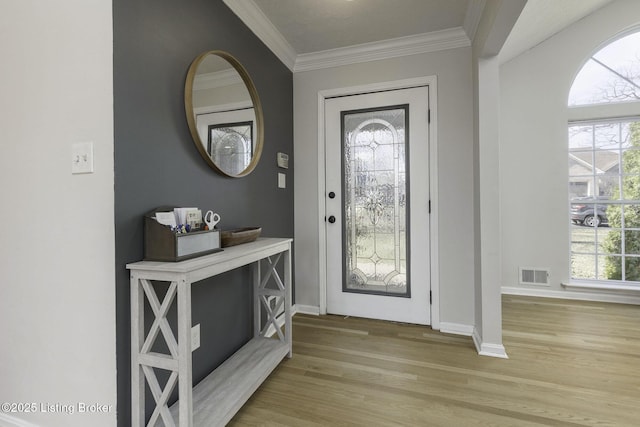 foyer entrance with visible vents, baseboards, light wood-style flooring, and crown molding