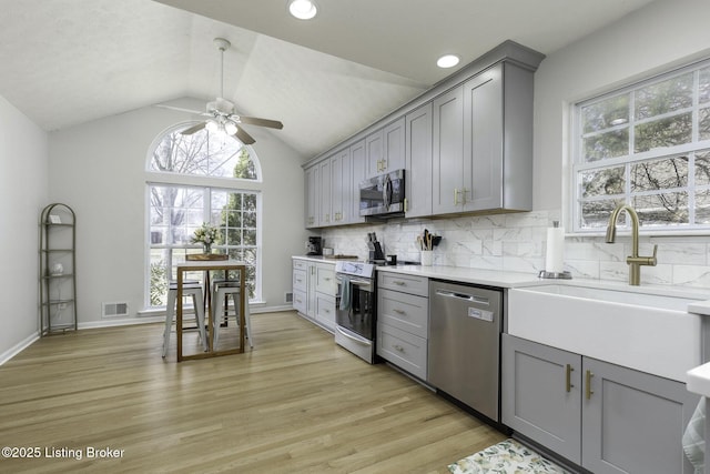 kitchen with a sink, visible vents, appliances with stainless steel finishes, and gray cabinetry