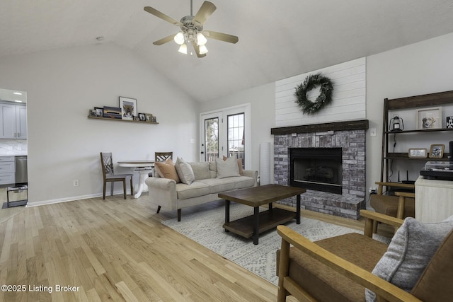 living room featuring high vaulted ceiling, a ceiling fan, light wood-style floors, a fireplace, and baseboards