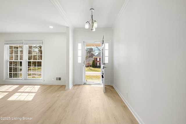 entrance foyer with a notable chandelier, baseboards, light wood-type flooring, and ornamental molding