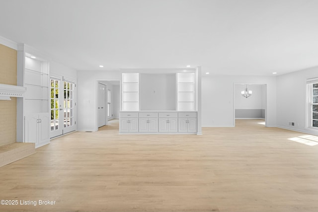 unfurnished living room with baseboards, an inviting chandelier, light wood-style flooring, recessed lighting, and french doors