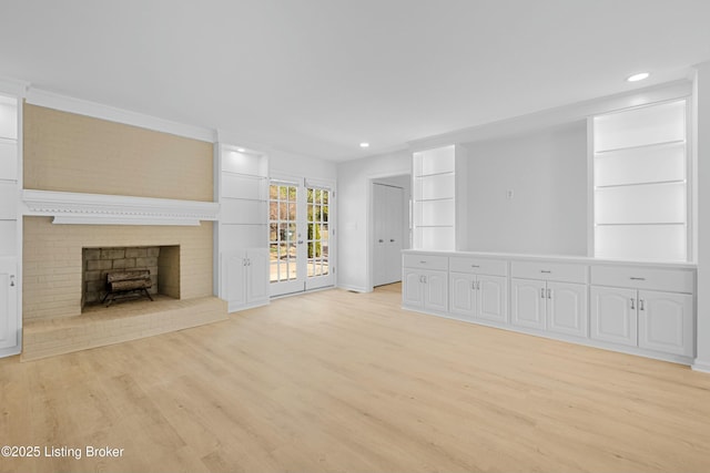 unfurnished living room featuring recessed lighting, light wood-style flooring, built in shelves, and a fireplace